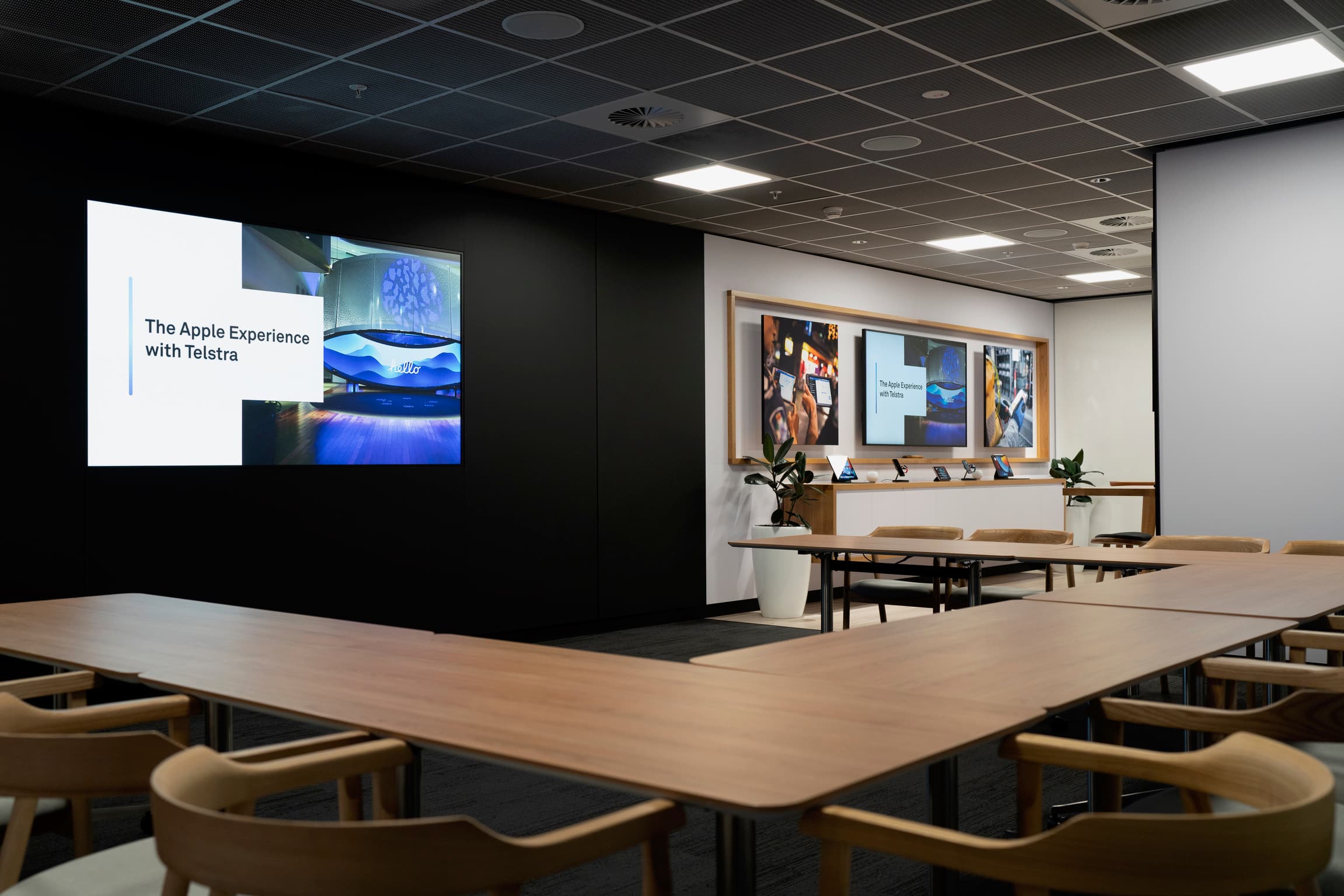 The Apple Experience with Telstra workshop space, with presentation screens and devices.